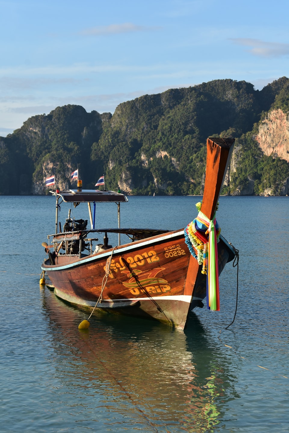 A traditional wooden longtail boat moored near limestone cliffs.