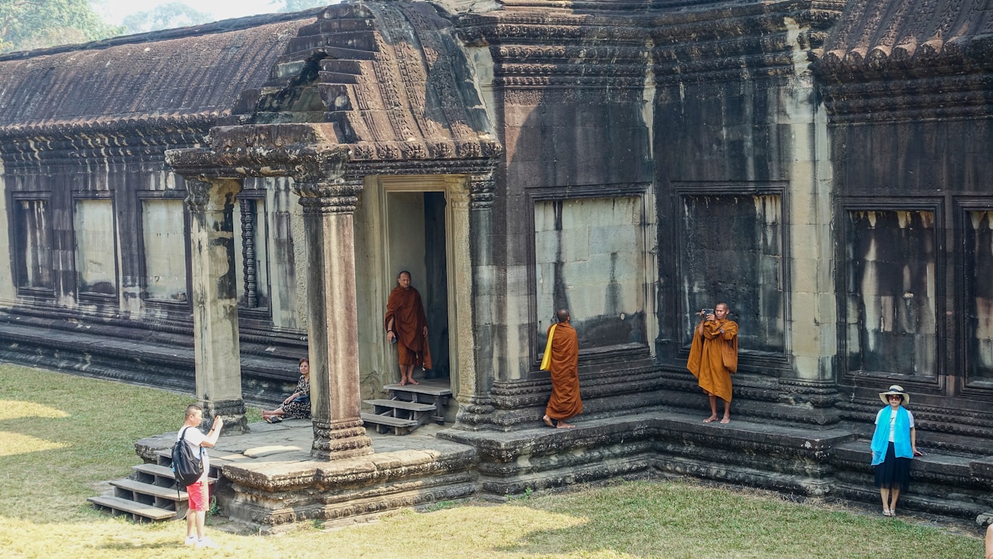 Tourists and monks explore an ancient stone temple complex.