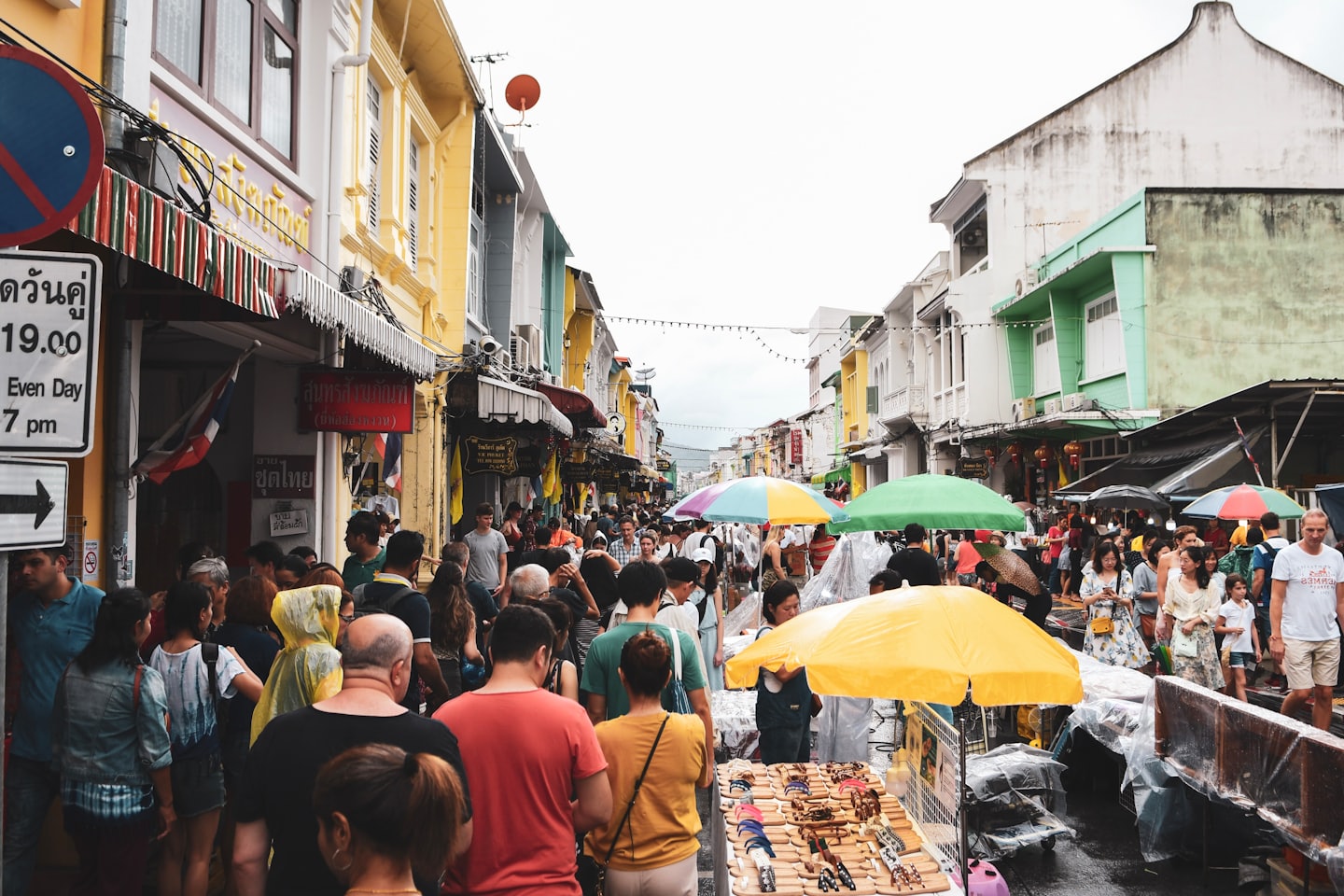 Shoppers browse stalls at a crowded outdoor street market.