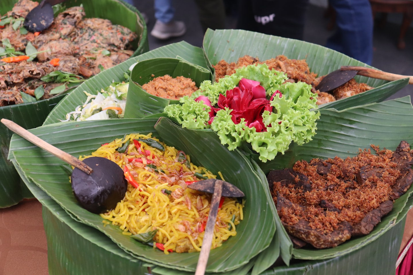 Traditional dishes served in banana leaf containers with wooden spoons.