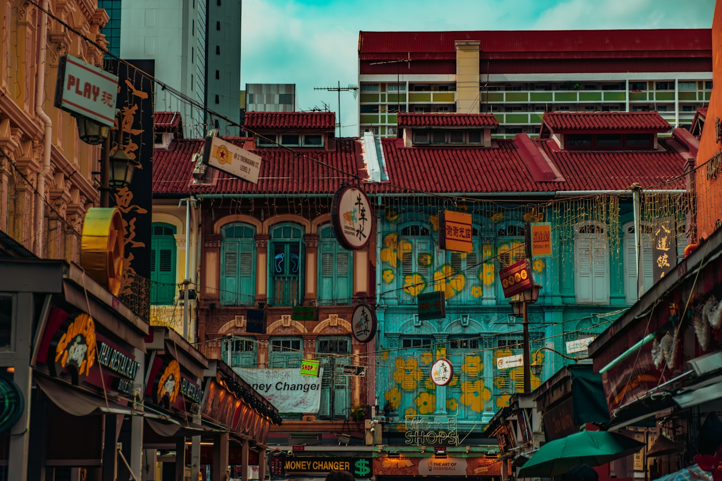 Traditional shop buildings feature bilingual signs under a clear blue sky.