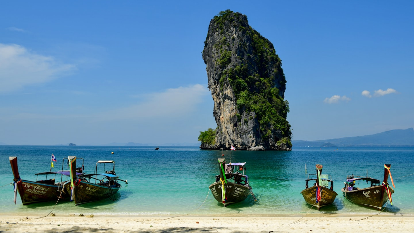 Traditional Thai longtail boats moored on a tropical beach.