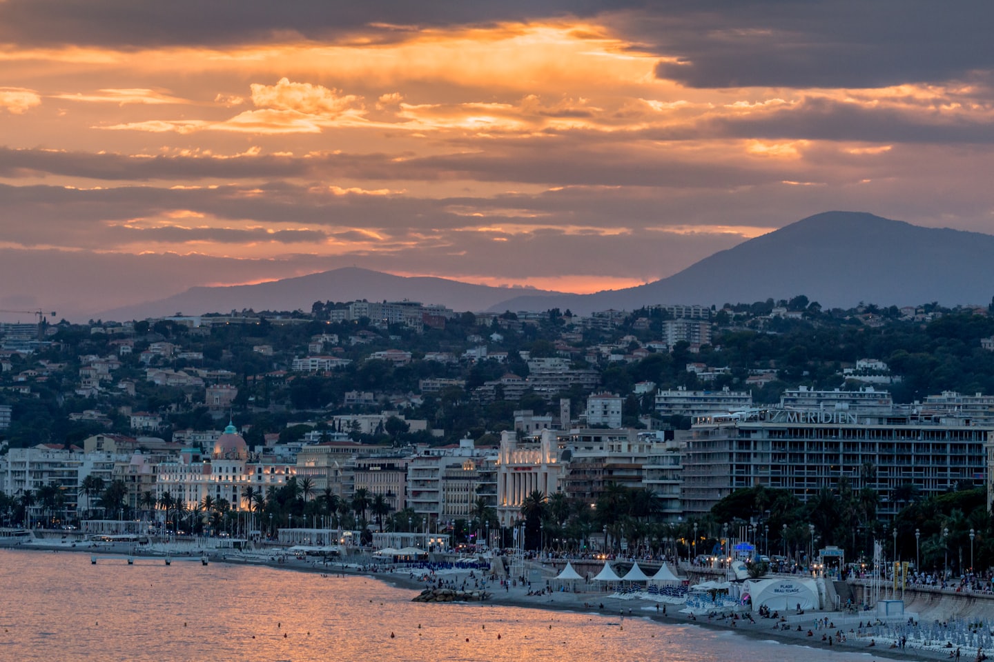 Coastal city buildings and beach at sunset.
